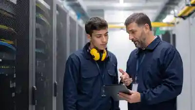 Early-career technician receiving guidance from an experienced data center mentor